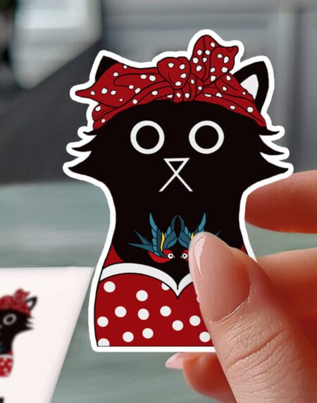a vinyl sticker depicting a black tattooed cat, in a red polka-dot dress and headscarf