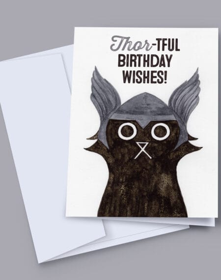 A 7x5 inch birthday card featuring an ink and salt black cat illustration wearing Thor's helmet