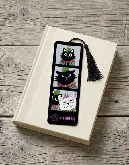 A black cat with a green mohawk poses in a photo booth strip — going from proud to irritated to bemused as a white cat photobombs the session. A punk cat bookmark on a black background with a black tassel, 52mm x 148mm, 400gsm matt laminated. Branded "Meowmento" at the bottom.
