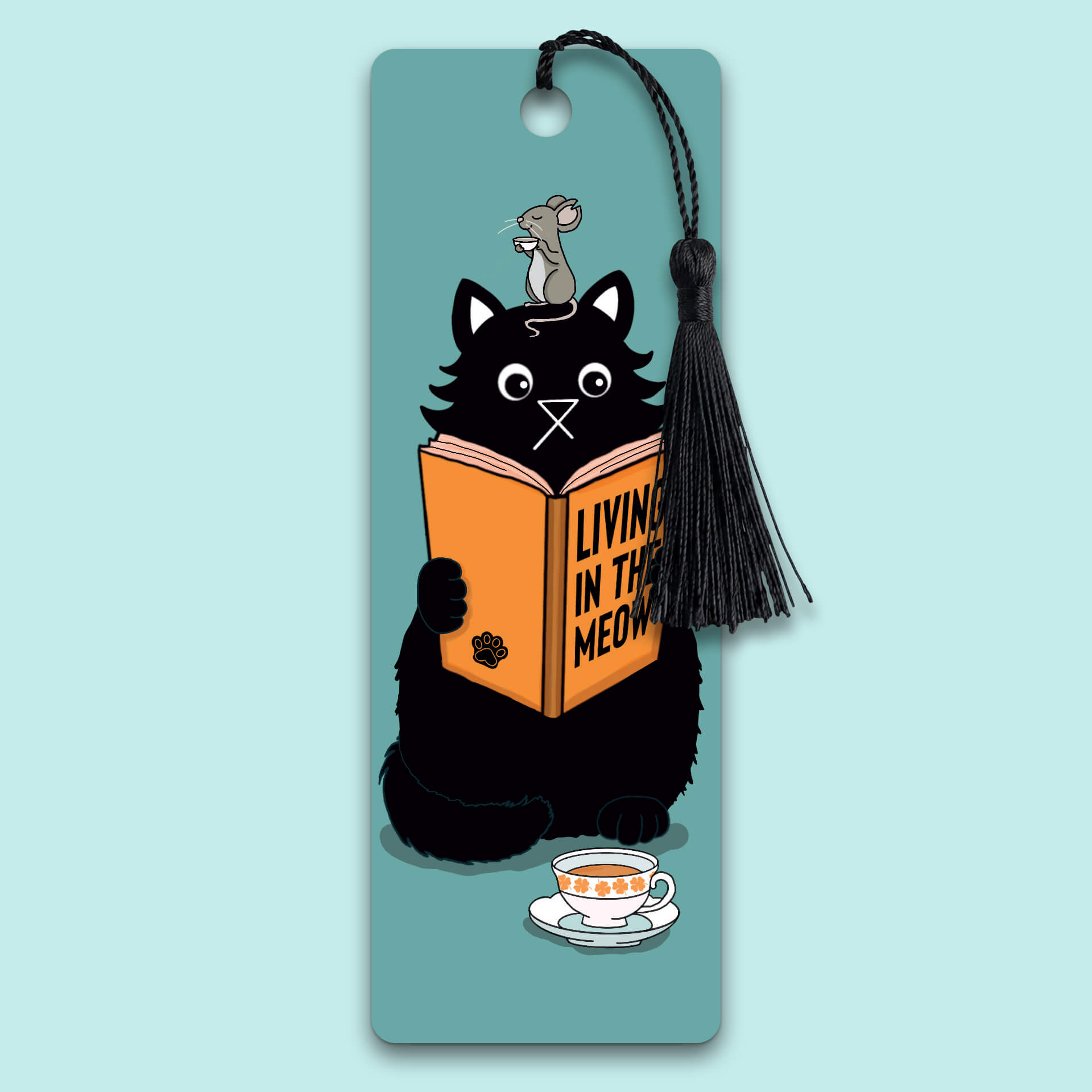 A bookmark featuring a black cartoon cat reading a book titled "Living in the Meow" with a mouse sitting on its head enjoying a cup of tea